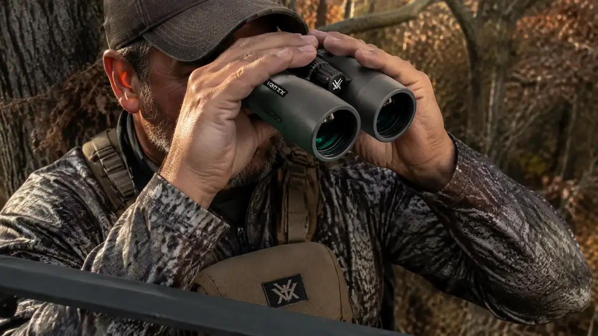 Hunter holding the Vortex Crossfire HD 10x42 binoculars with the GlassPak harness attached