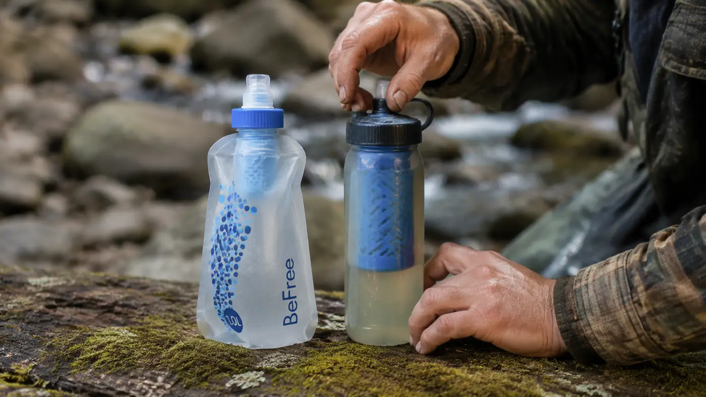 Katadyn BeFree soft flask filter and a LifeStraw squeeze filter set side by side on a weathered log for comparison